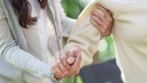 Frau stützt älteren Angehörigen am Arm, Kündigung bei Pflege von Angehörigen